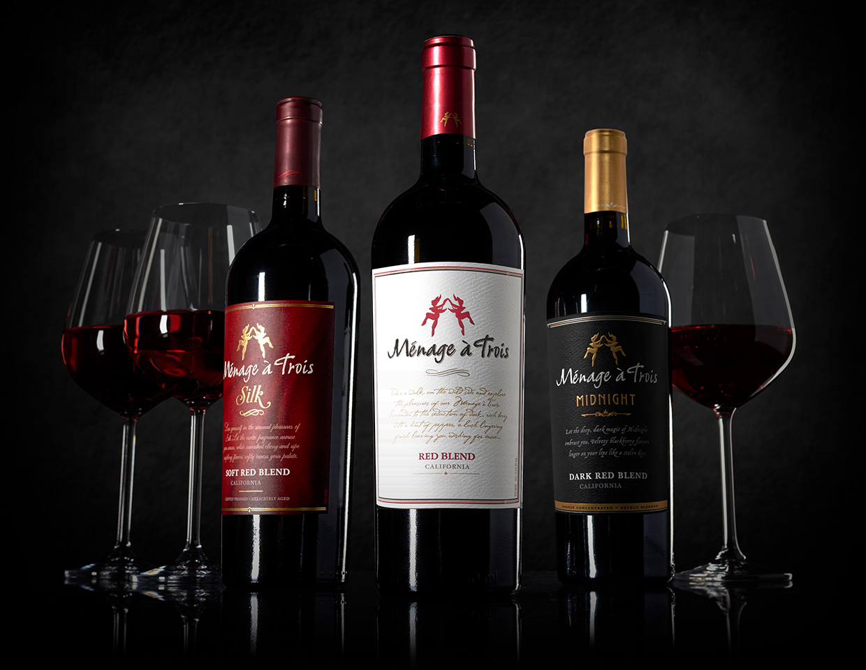 bottle lineup of three menage a trois red wines, silk soft red blend, california red blend, and midnight dark red blend.