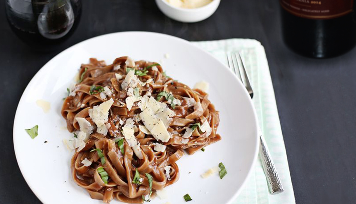 Plate of one pot red wine pasta with basil and parmesan cheese.