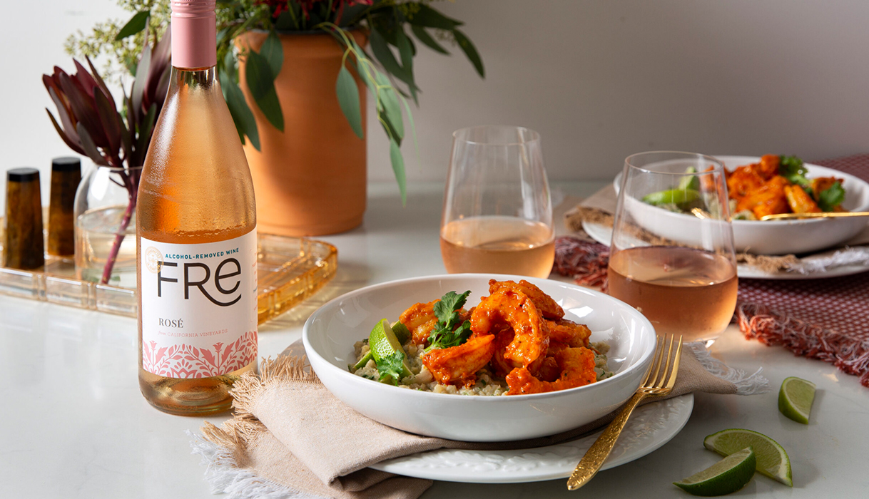 a bowl of red curry shrimp and rice next to glasses of FRE alcohol-removed rose.