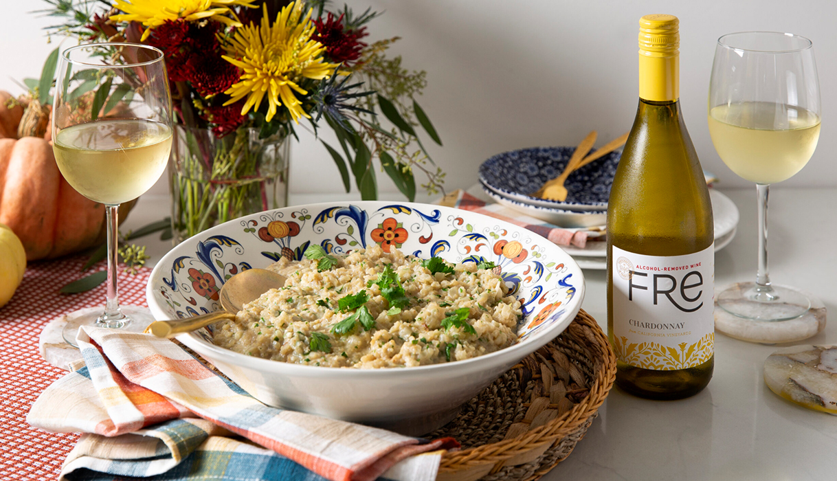 Bowl of creamy coconut cilantro cauli-rice next to glasses of FRE alcohol-removed chardonnay with fall decorations in the background.