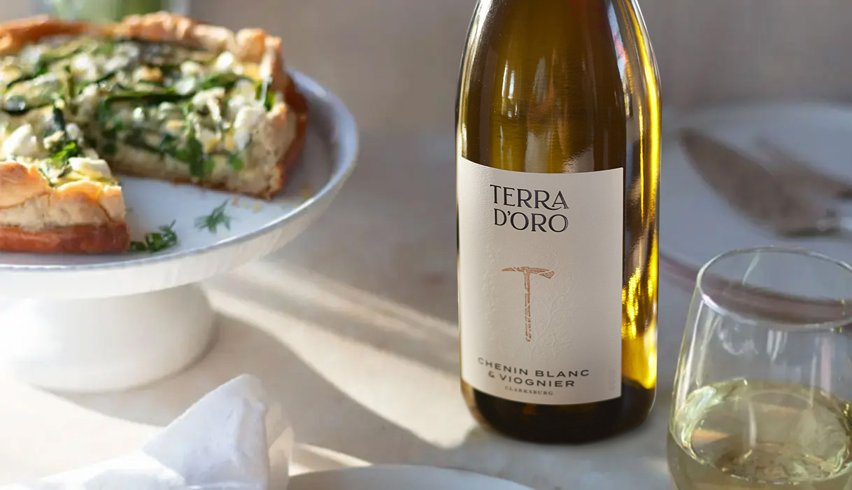 A spring quiche on a white dish next to a bottle and glass of Terra d'Oro Chenin Blanc & Viognier. Learn how to make this quiche recipe from One Stop Wine Shop.