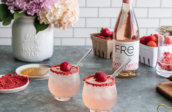 http://a%20bottle%20and%20glasses%20of%20FRE%20rose%20on%20a%20table%20with%20containers%20of%20strawberries%20in%20the%20background